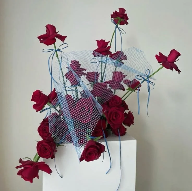 Red roses tied with blue ribbon on a white plinth, sky blue and maroon wedding flowers