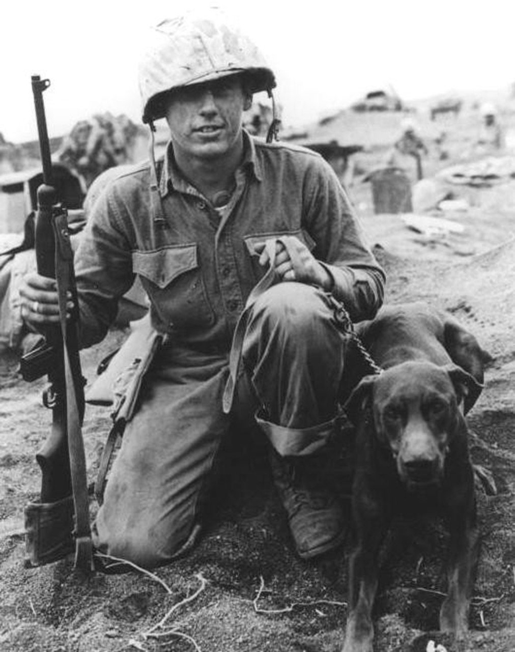  Grinning, U.S. Marine Private Francis Hall, stationed in Iwo Jima, poses with his Doberman dog. 