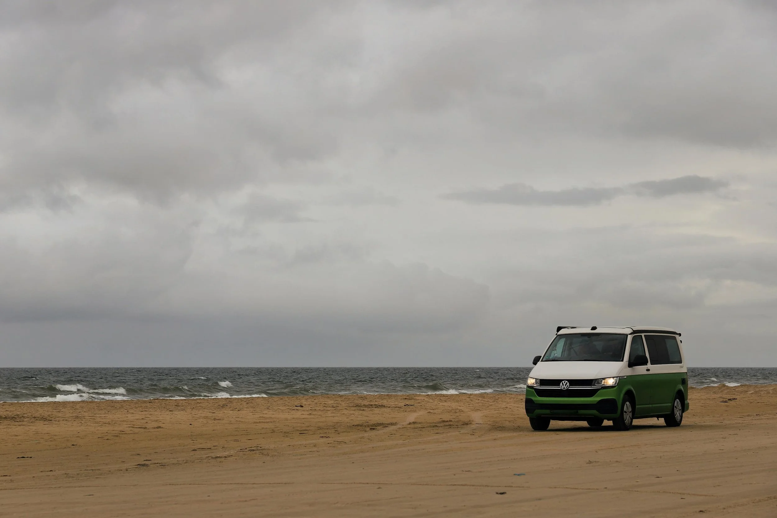 Volkswagen Transporter campervan parked on a beach, demonstrating the versatile mid-size van used for many UK camper conversions | which VW campervan size is right for you | Cornwall