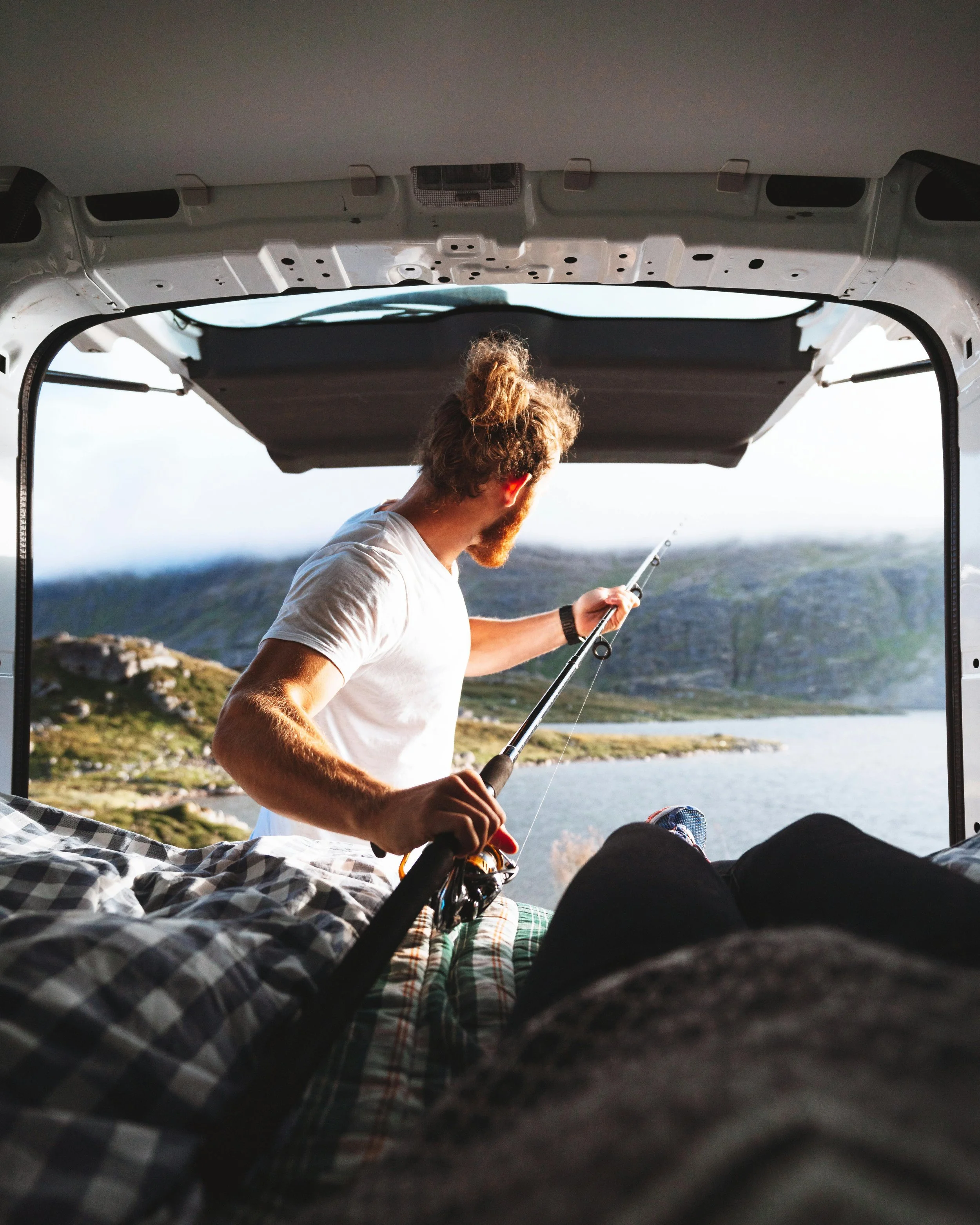 Campervan without van lining and man fishing from the tailgate | van ply lining kit | Cornwall