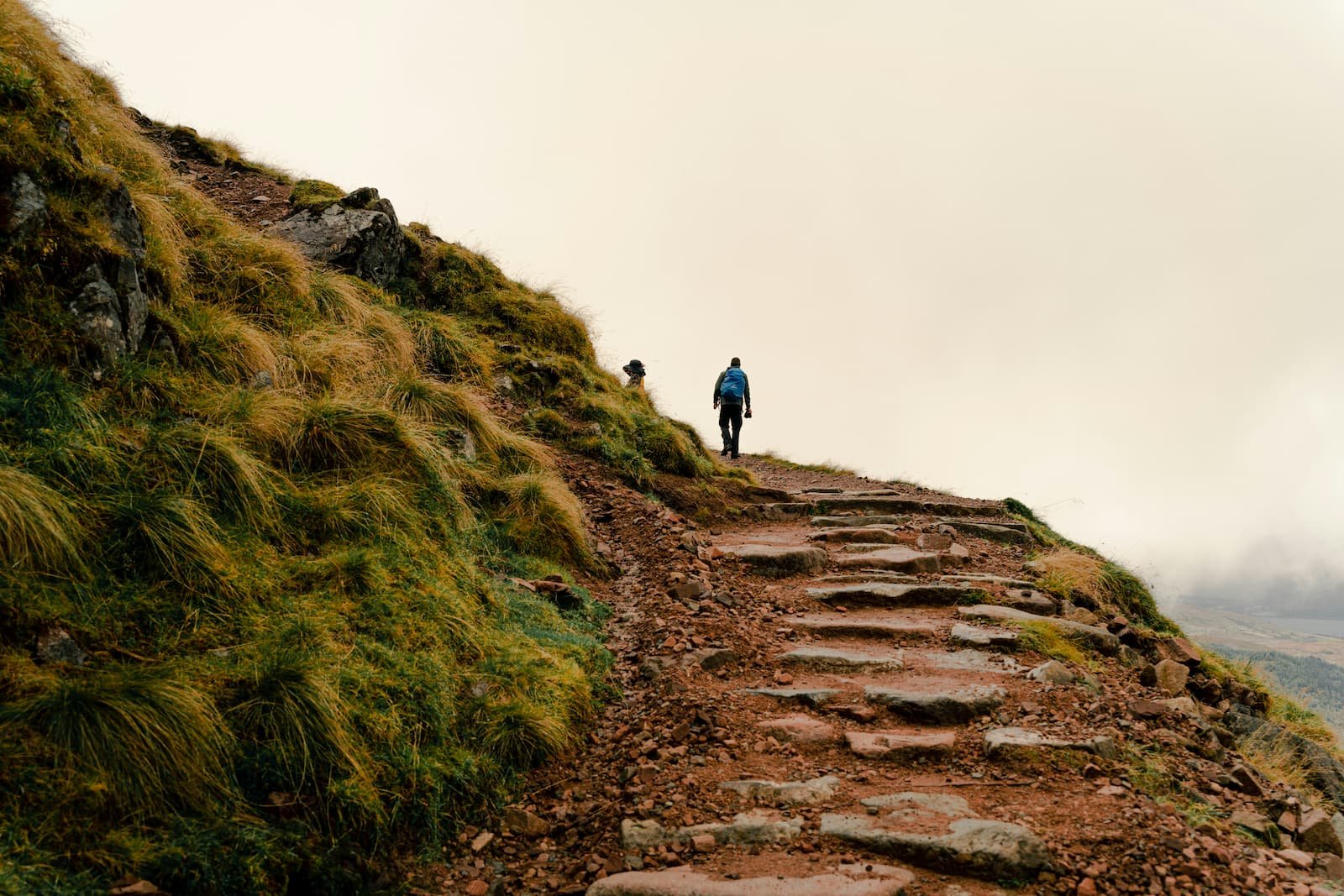 Hiker climbing a rugged mountain path representing the outdoor travel lifestyle supported by campervans | Wild Earth Campers| Cornwall