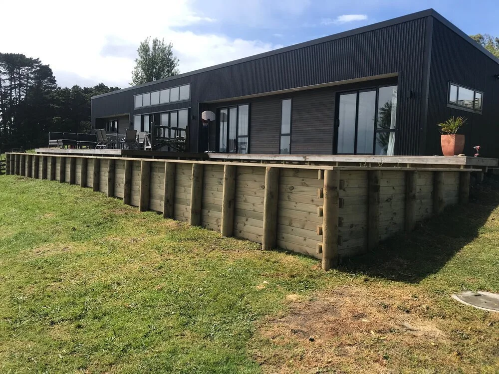 Timber retaining wall around a black house