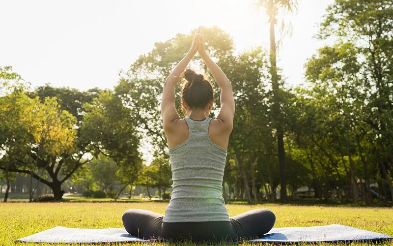 young asian woman yoga outdoors meditates while practicing yoga