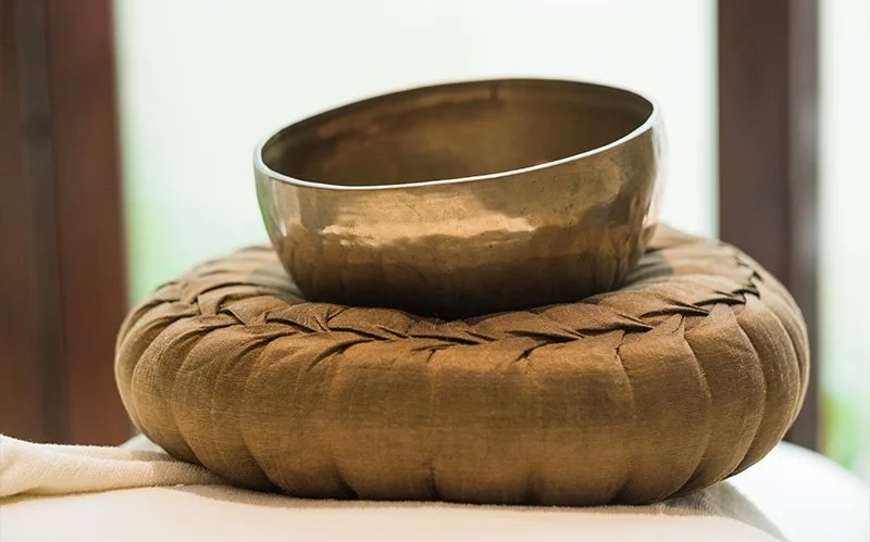 A traditional bronze Tibetan singing bowl resting on a cushion