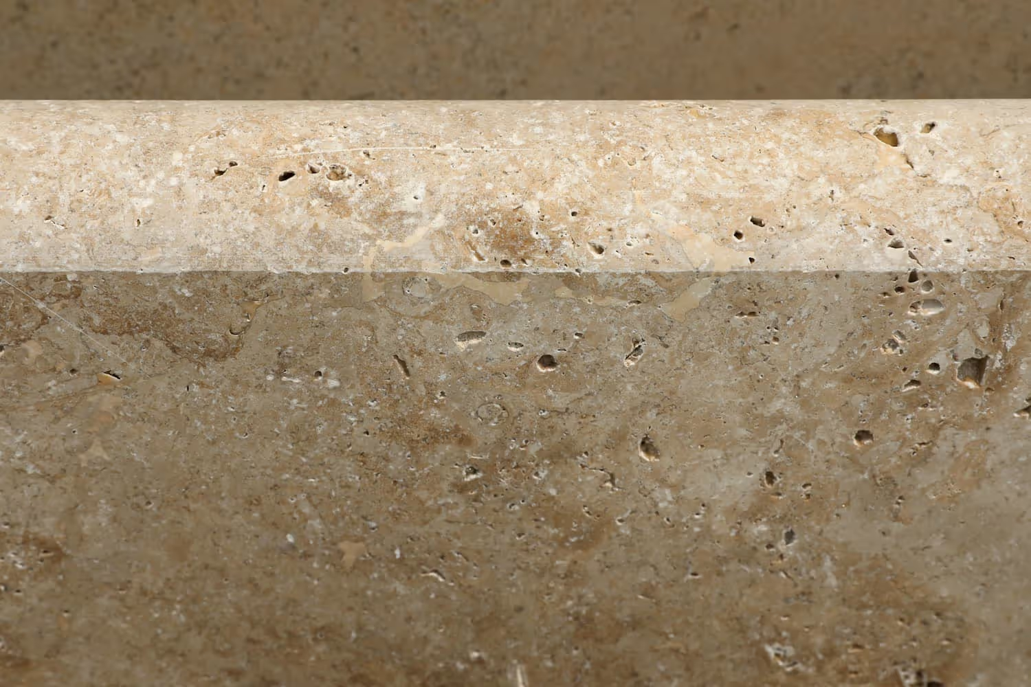 Close-up of a beige granite countertop with a polished surface and small natural holes and flaws.