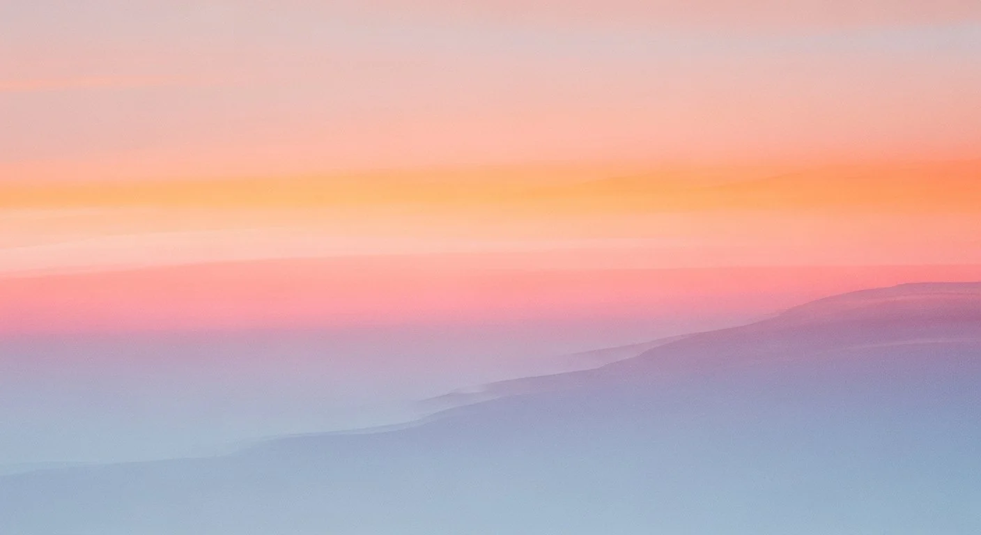 A soft, colorful sunset over a mountain range with pastel pink, purple, and blue hues.