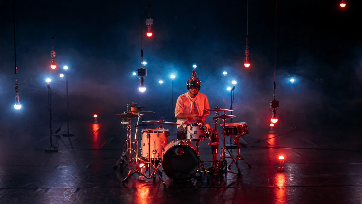 Drummer on stage under hanging red and blue Astera NYX Bulbs