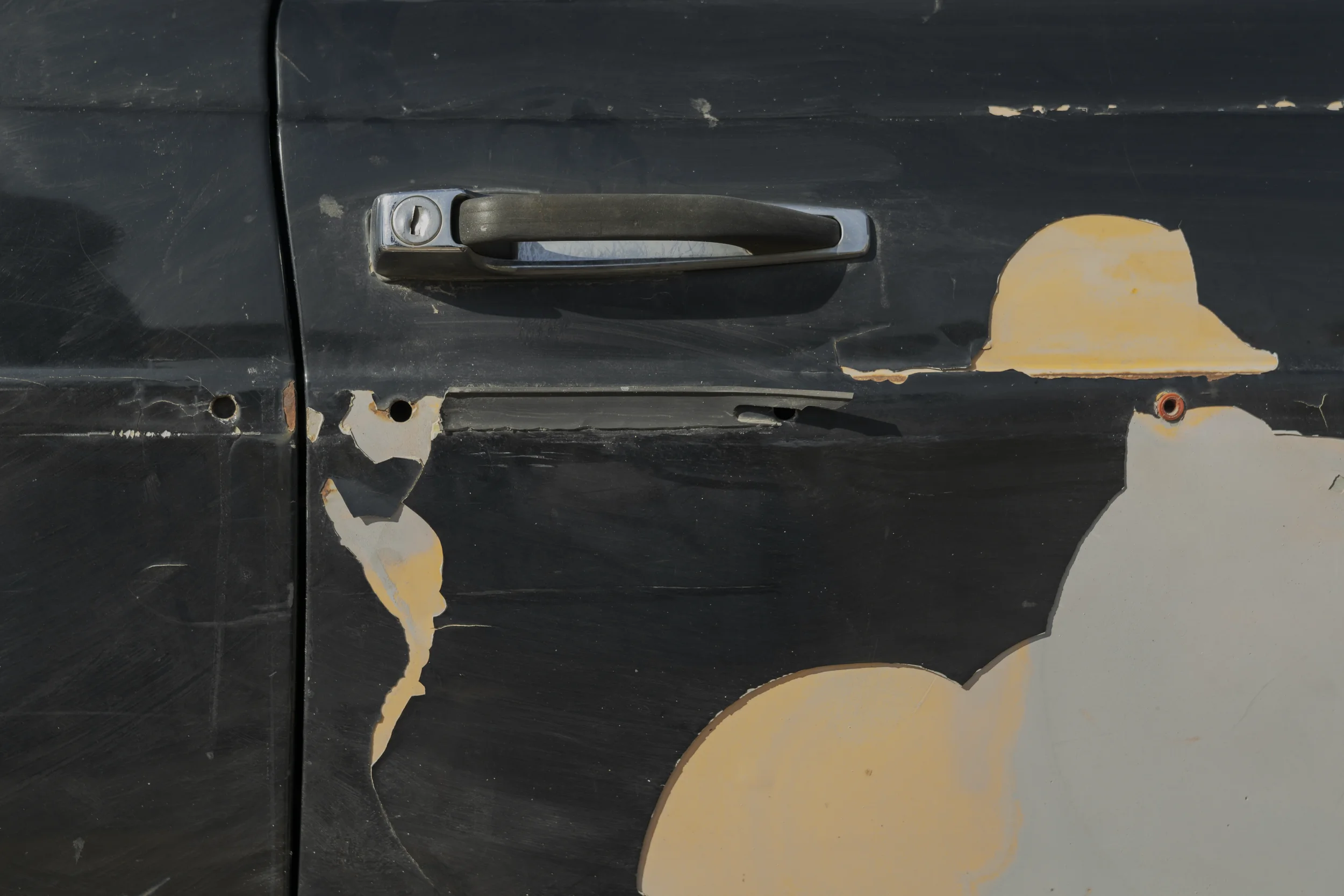 The black door of the Mercedes bears deep scratches and peeling paint. The worn handle becomes a quiet record of repeated journeys, repairs and hands that keep opening the way forward.
Ramallah - November 2025