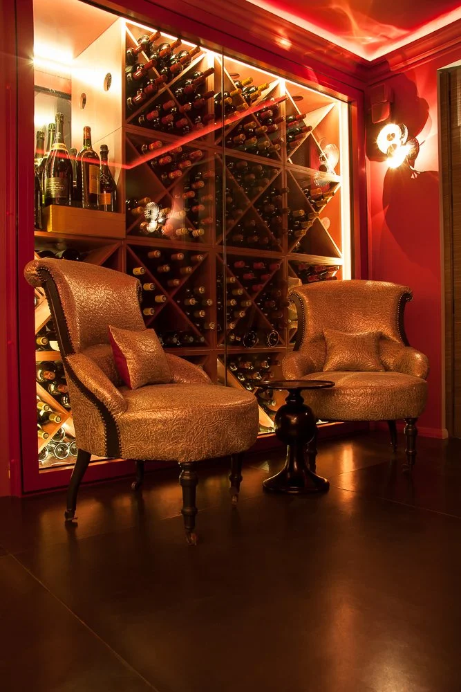 Private home wine cellar with glass-front storage and armchairs, interior design photography Chelsea