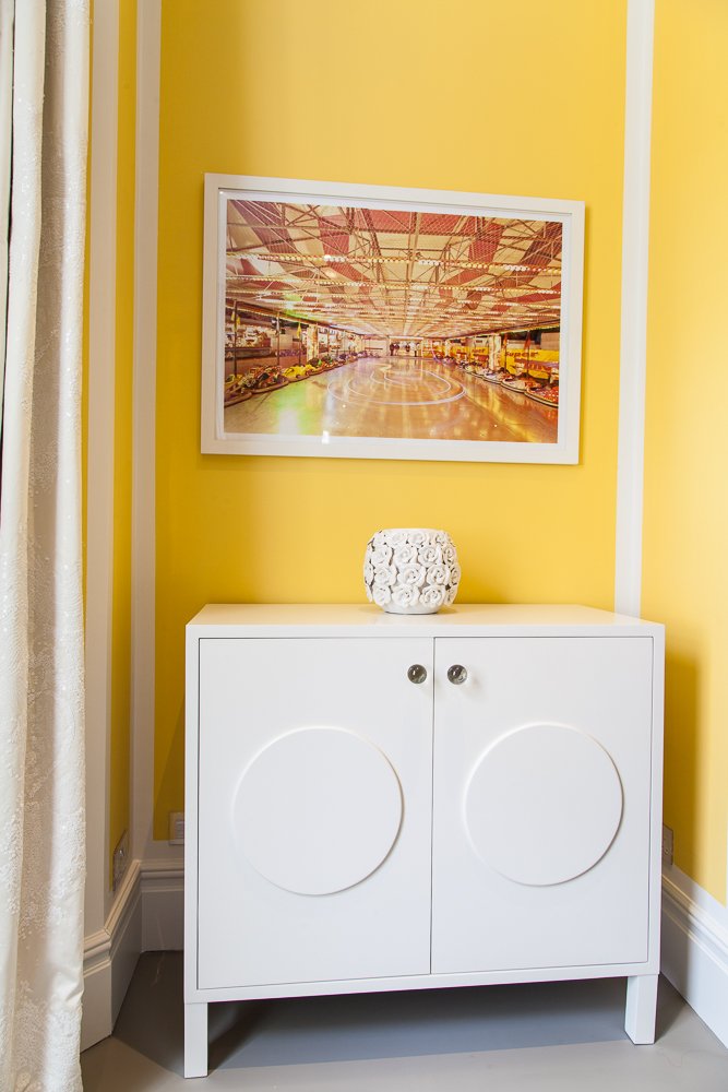 Console table with framed artwork against a yellow wall, interior design photographer London, Clapham