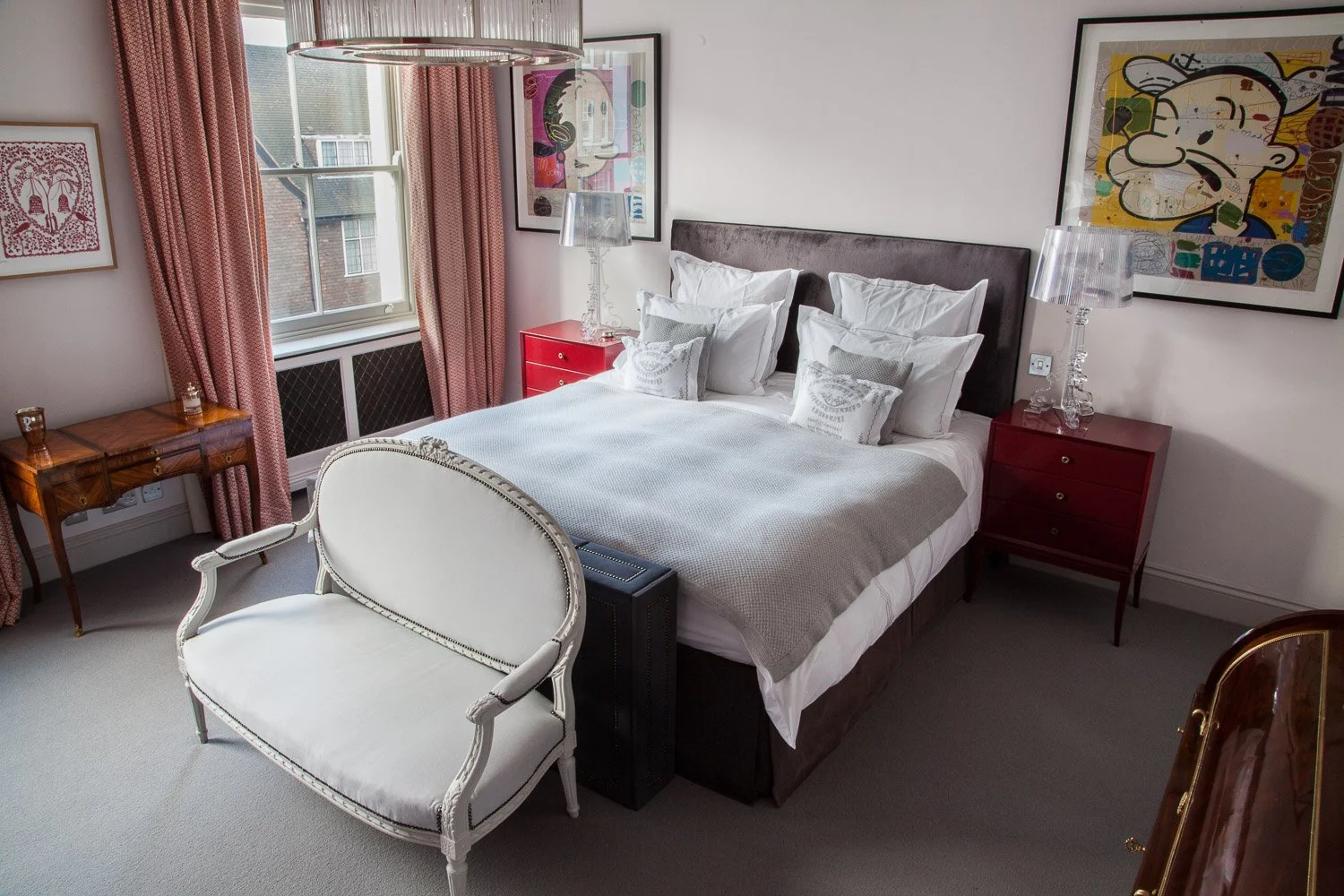 Bedroom with upholstered bench seat and layered artwork above the headboard, interior photographer London, Chelsea