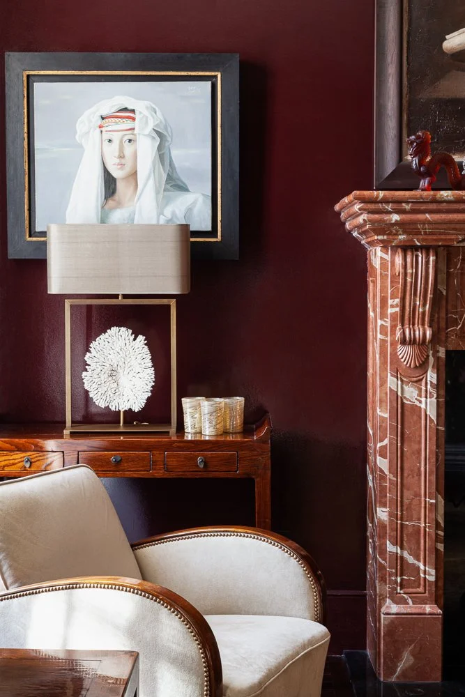 Isabelle Bizard table lamp with a white coral display piece, on a wooden console beside a framed portrait, interior photography