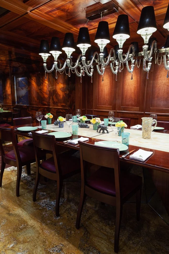Isabelle Bizard Murano glass pitcher and drinking glasses on a dining table, set for dinner in a wood-panelled dining room, interior design photography