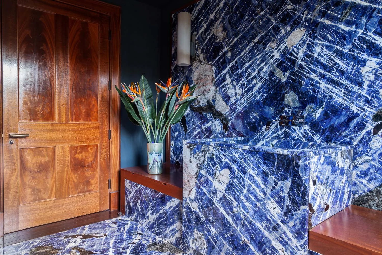 Isabelle Bizard Murano glass vase with bird of paradise flowers, in a bathroom with a sodalite blue stone wall, interior photographer London