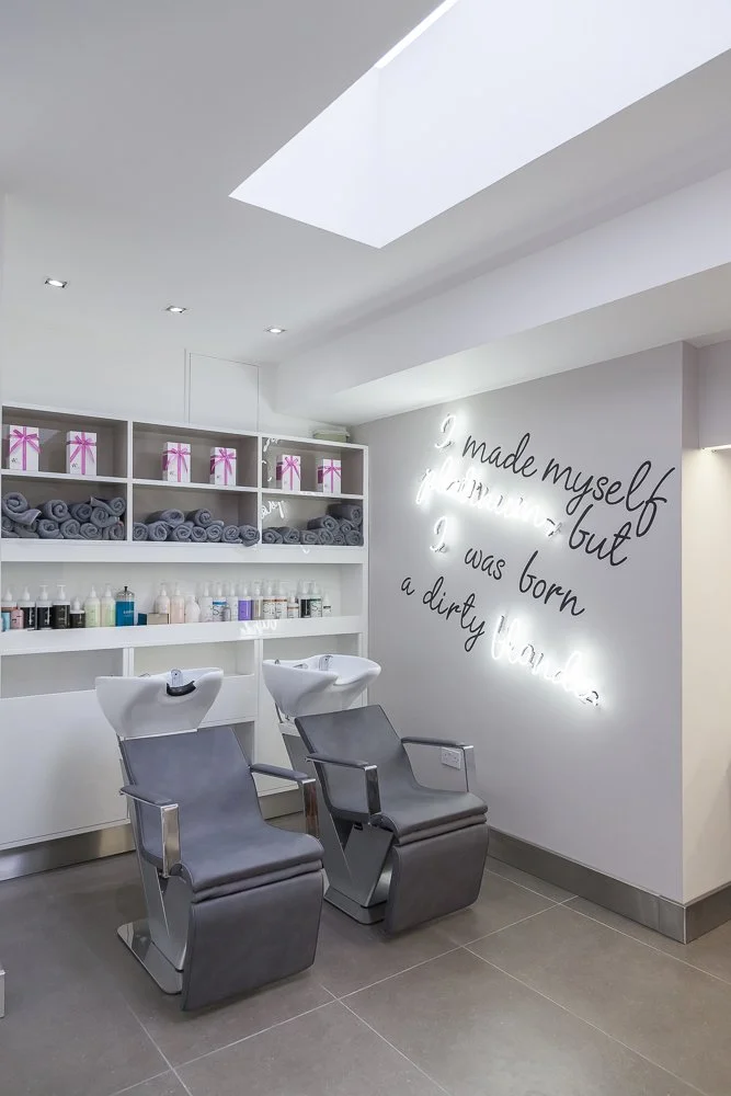 Hair salon wash area with illuminated neon quote on the wall, interior photography