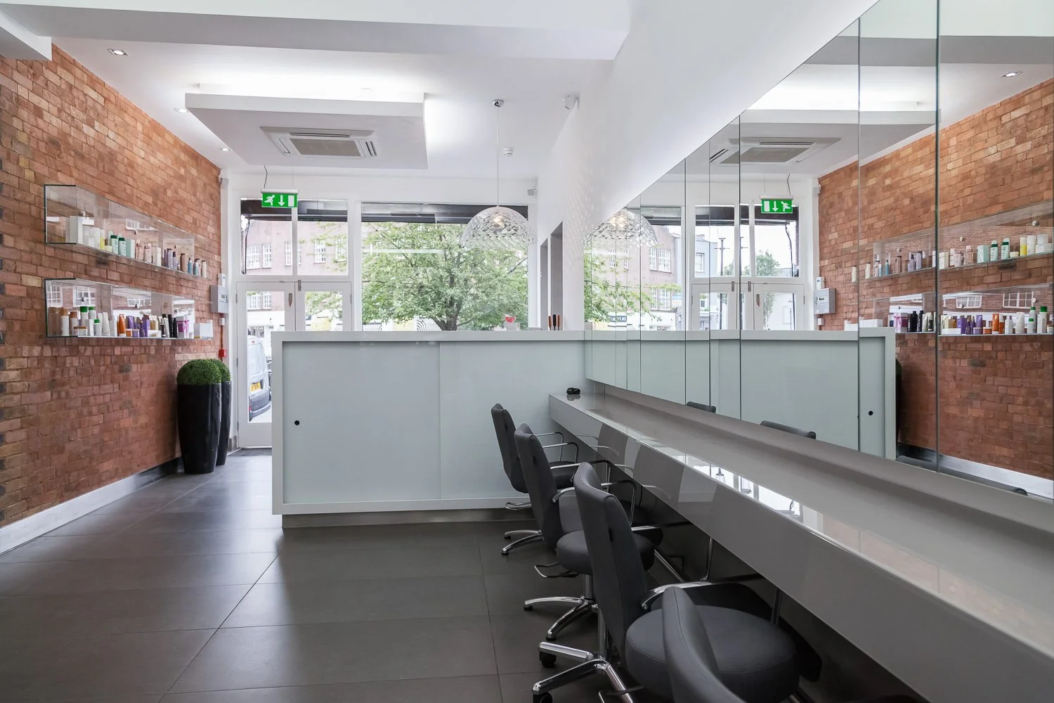 Hair salon reception area with exposed brick wall and glass entrance, interior design photographer London