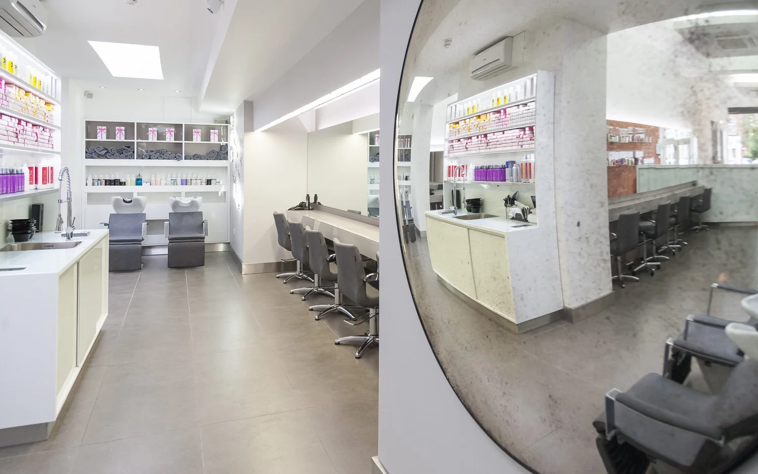 Wide view of hair salon styling stations along an exposed brick wall, interior photographer London