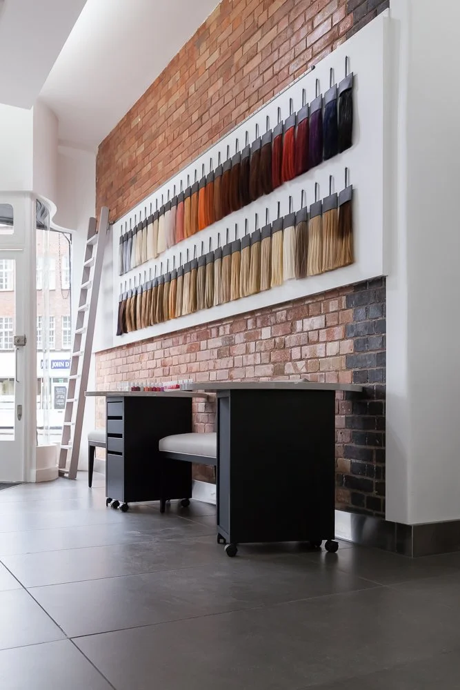 Hair colour swatch display wall beside an exposed brick staircase, interior photographer