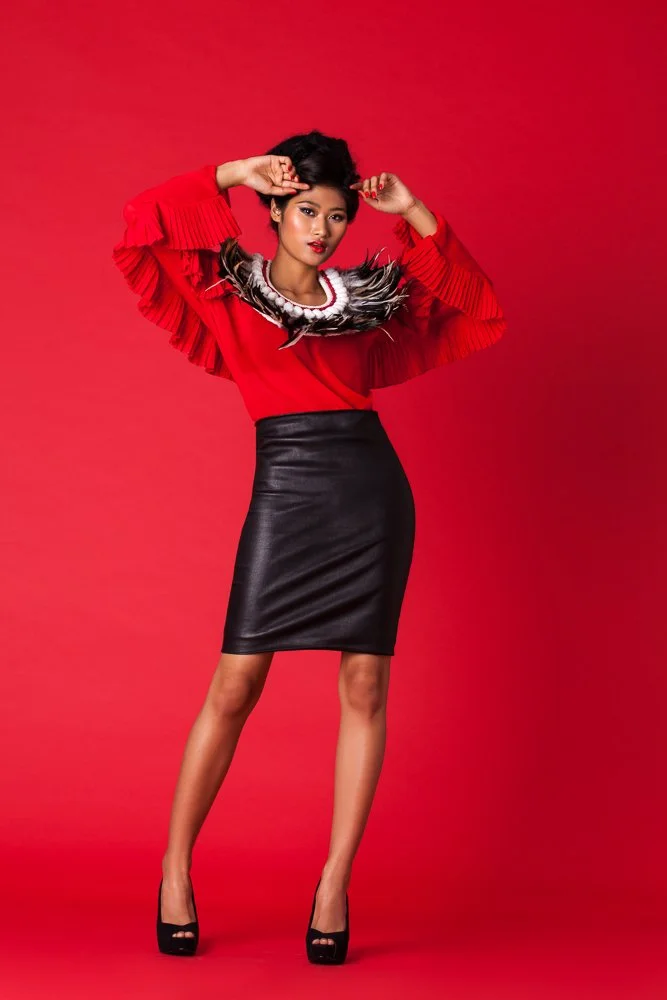 Model in a red ruffled top and black skirt, dynamic pose against a red backdrop, styled and art directed by Laurence Trolet, fashion and editorial photography