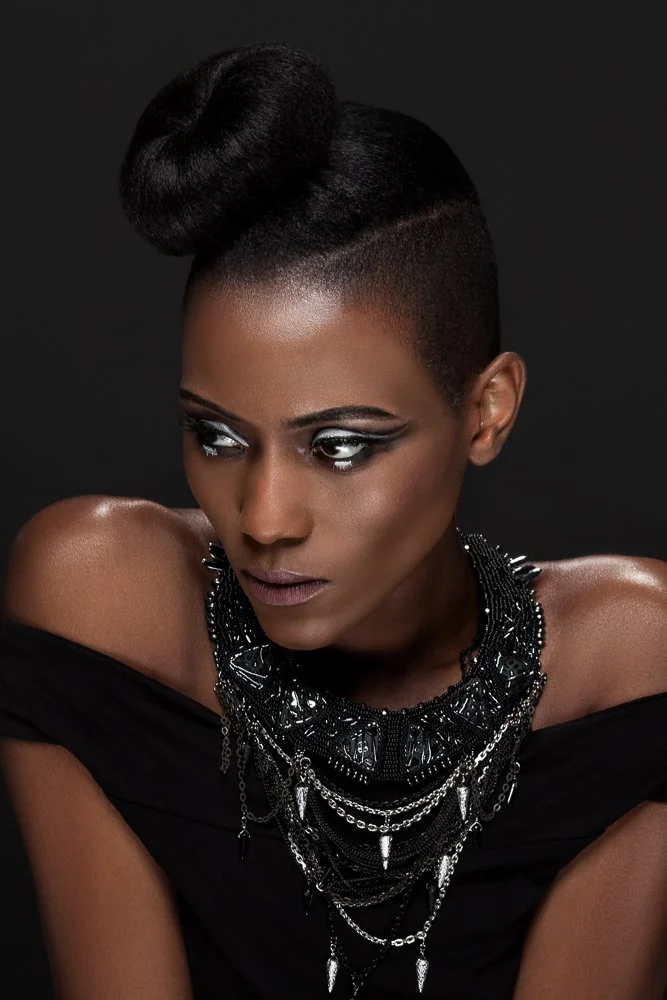 Close-up of a model with a sculpted bun, glancing aside, wearing a beaded bib necklace with silver chains, styled and art directed by Laurence Trolet, brand photographer