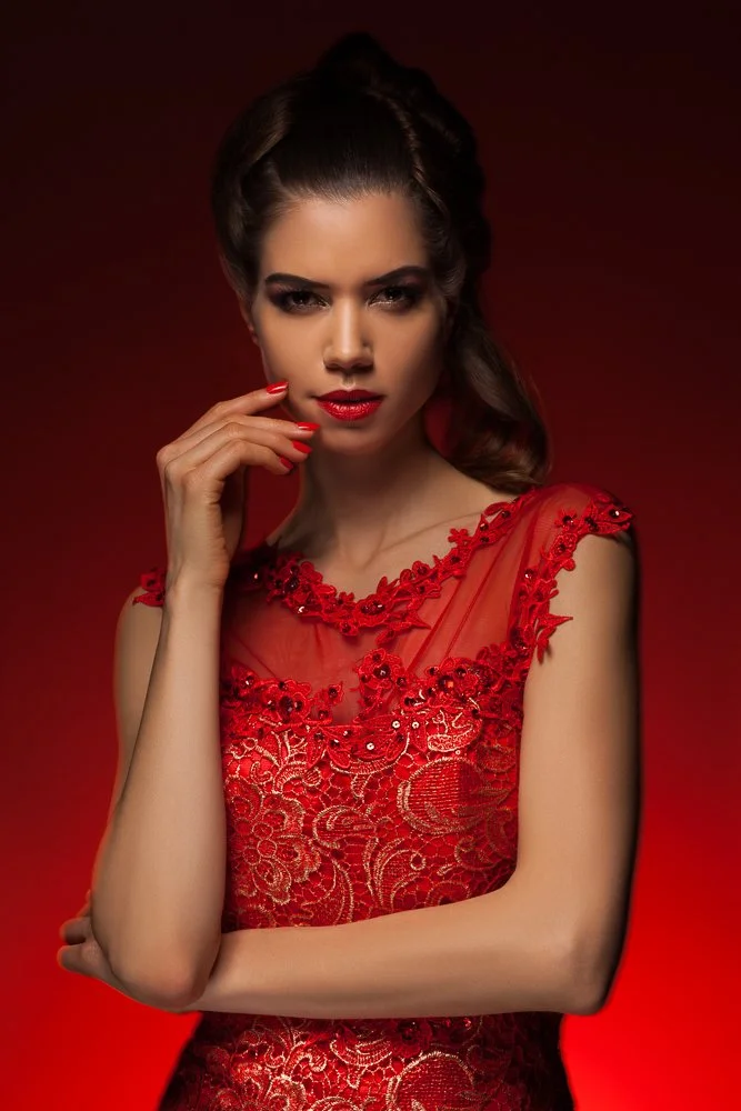 Close-up portrait of a model in a red lace gown, dramatic red lighting, styled and art directed by Laurence Trolet, fashion photographer