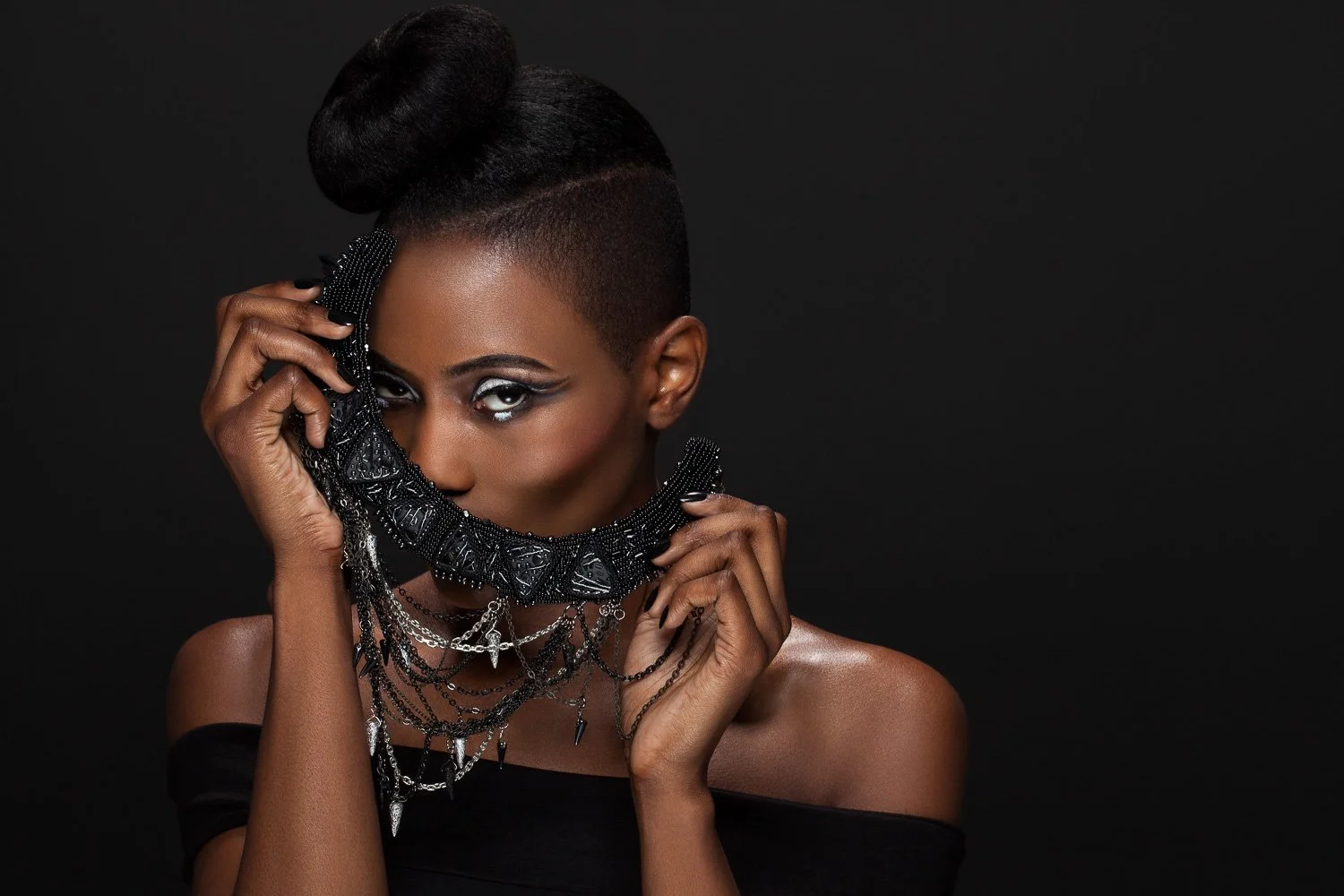 Model raising a beaded statement necklace to her face, off-shoulder black top, styled and art directed by Laurence Trolet, branding photography