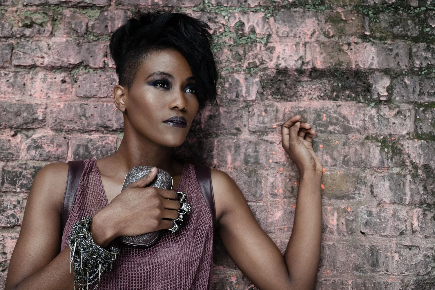 Model with a short textured updo against a brick wall, styled and art directed by Laurence Trolet, editorial photography
