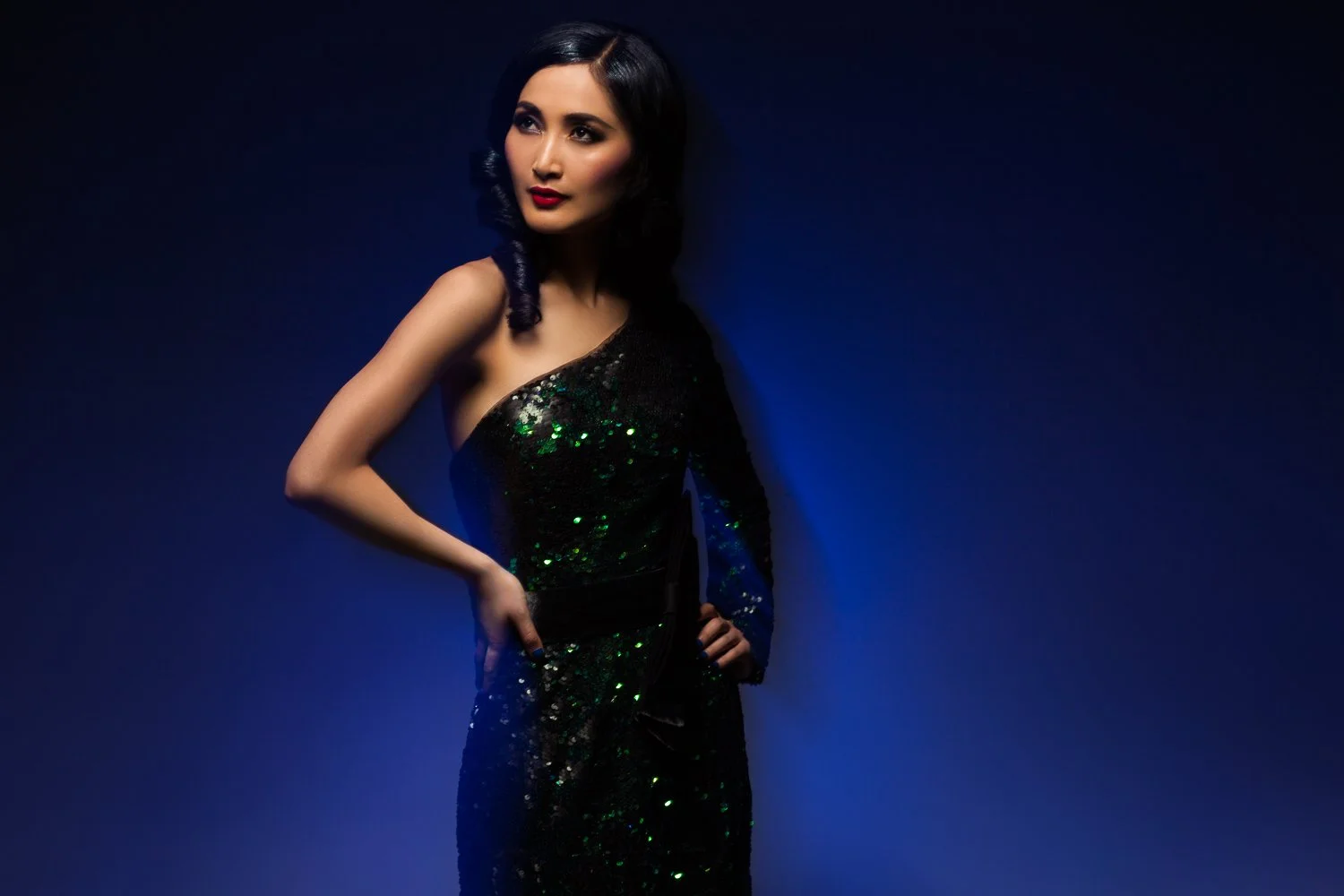 Model in a sequin dress, dynamic pose against a deep blue backdrop, styled and art directed by Laurence Trolet, editorial fashion photography