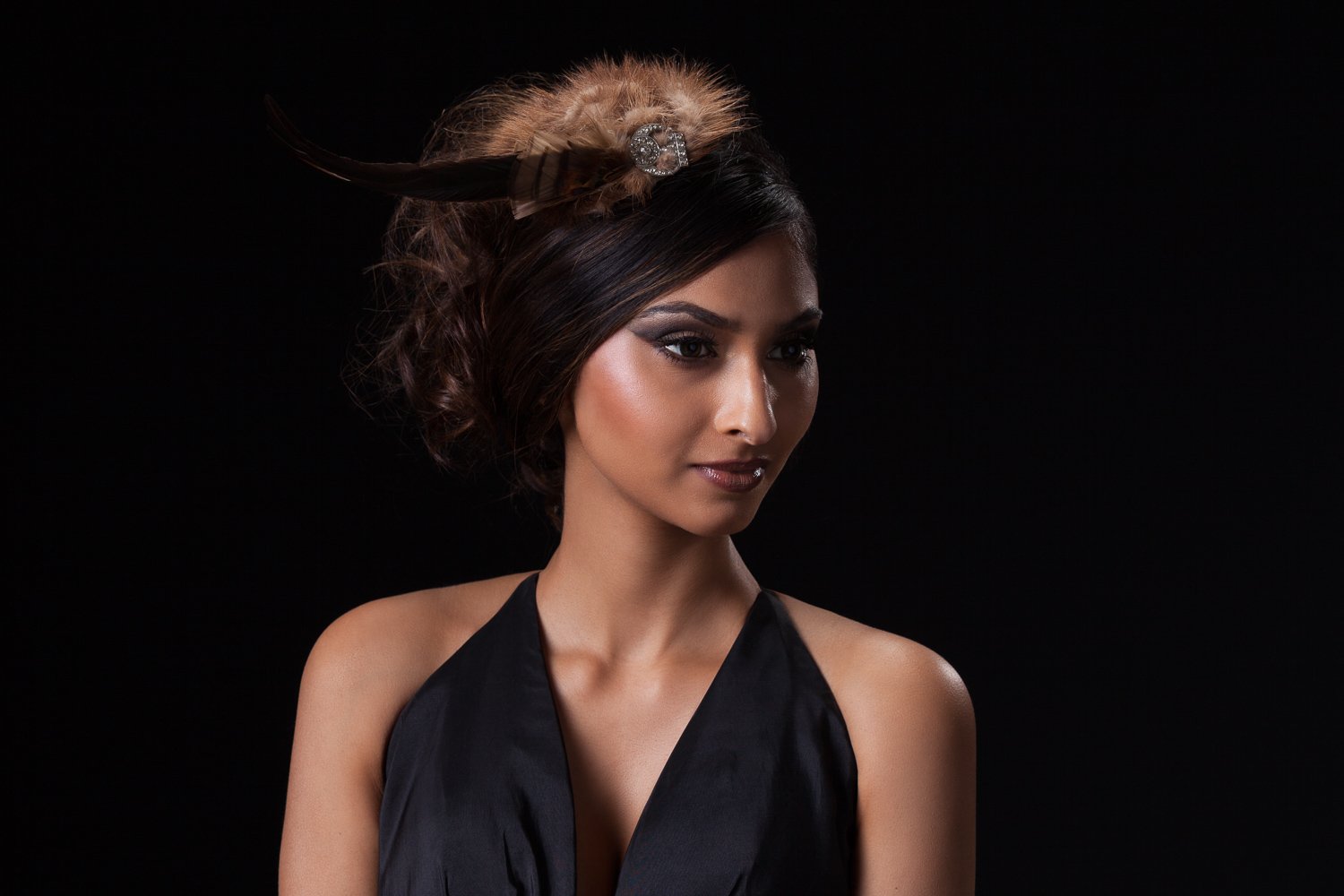 Model in a faux fur fascinator with a long feather and jewelled brooch, curled updo and black halter top, styled and art directed by Laurence Trolet, branding photographer