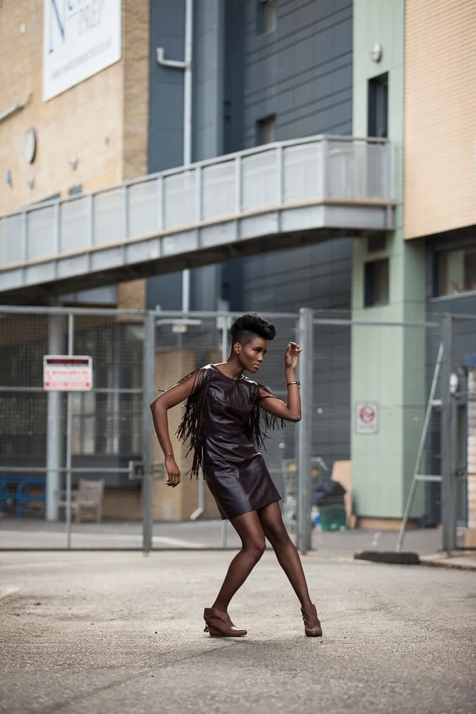 Model in a leather dress in an urban exterior setting, styled and art directed by Laurence Trolet, fashion and editorial photography