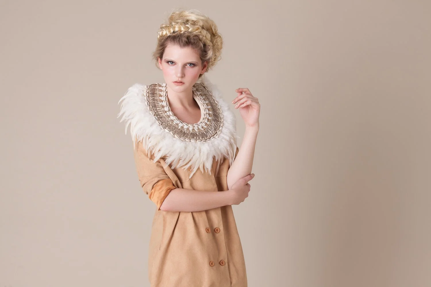 Portrait of a model with a layered beaded collar and tan coat, styled and art directed by Laurence Trolet, editorial photography