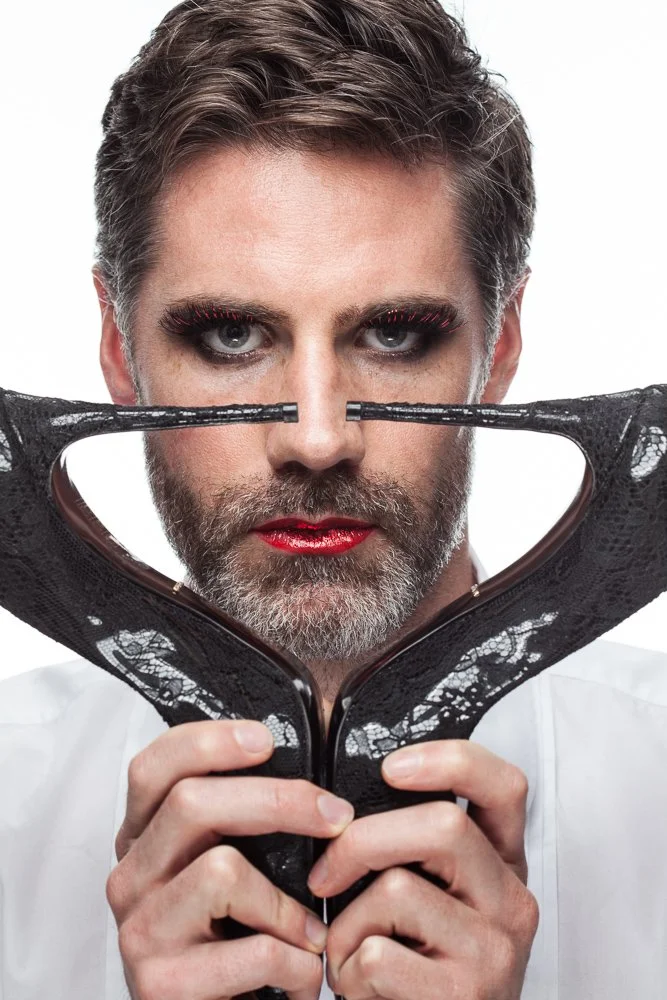 Male model holding a high-heeled shoe close to his face, styled and art directed by Laurence Trolet, editorial fashion photography