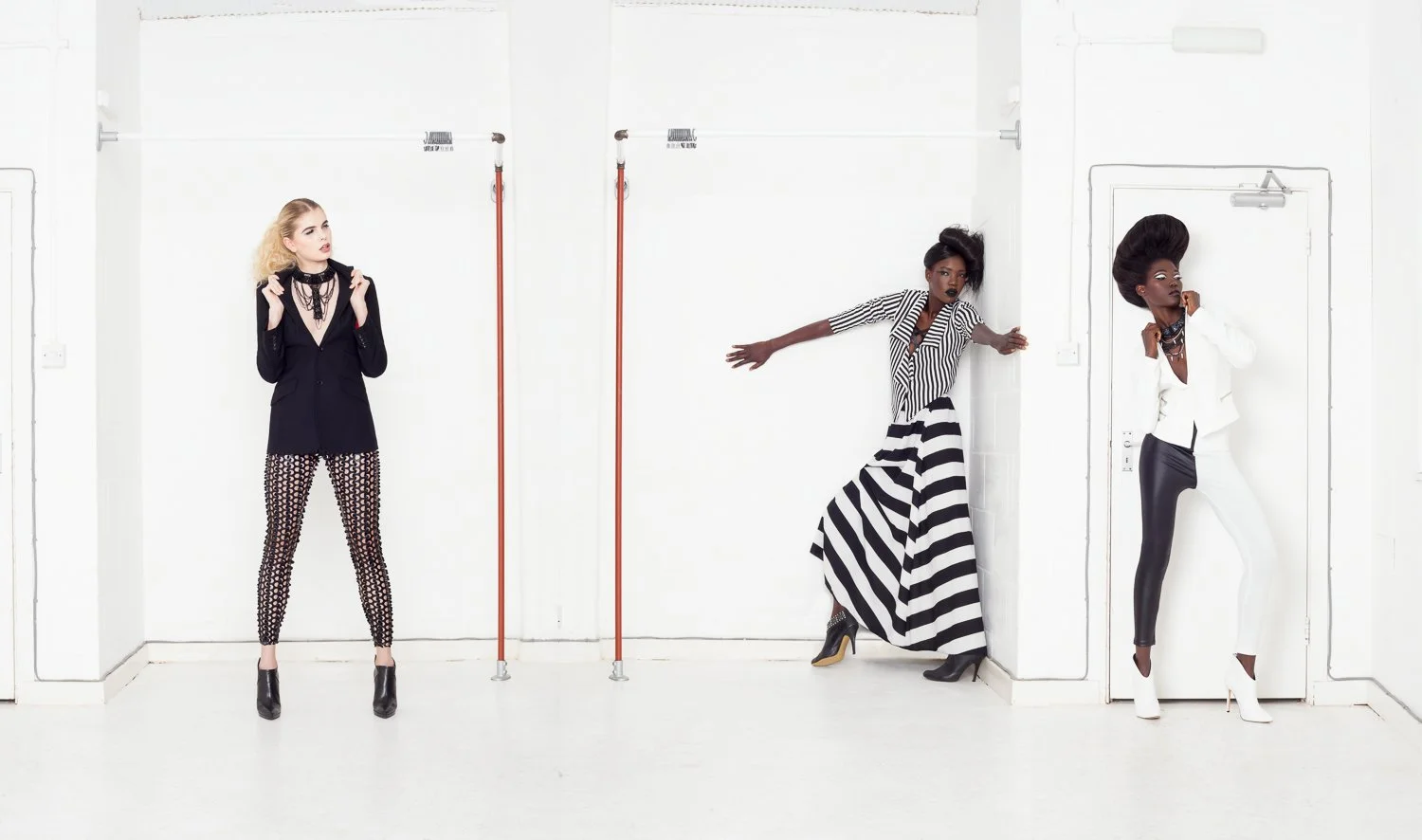 Three models in mixed black and striped outfits posing in a white studio, styled and art directed by Laurence Trolet, fashion and editorial photography