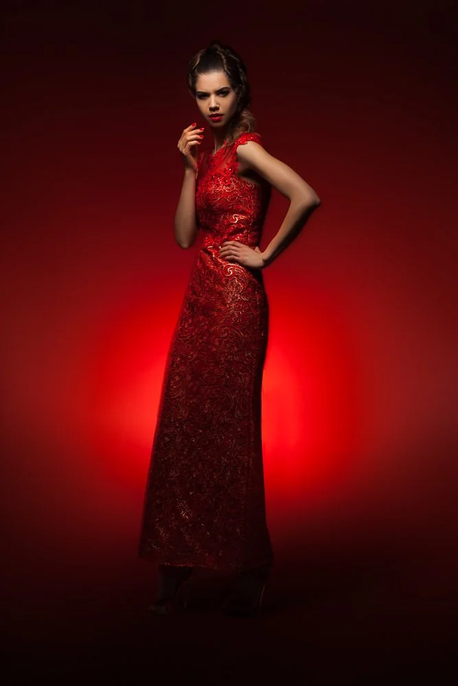 Model in a red sequin gown, side profile against dramatic red lighting, styled and art directed by Laurence Trolet, editorial fashion photography