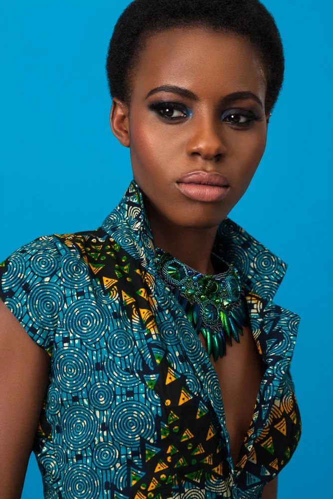 Portrait of a model in a blue and yellow geometric print top with a deep collar and statement necklace, styled and art directed by Laurence Trolet, branding photography