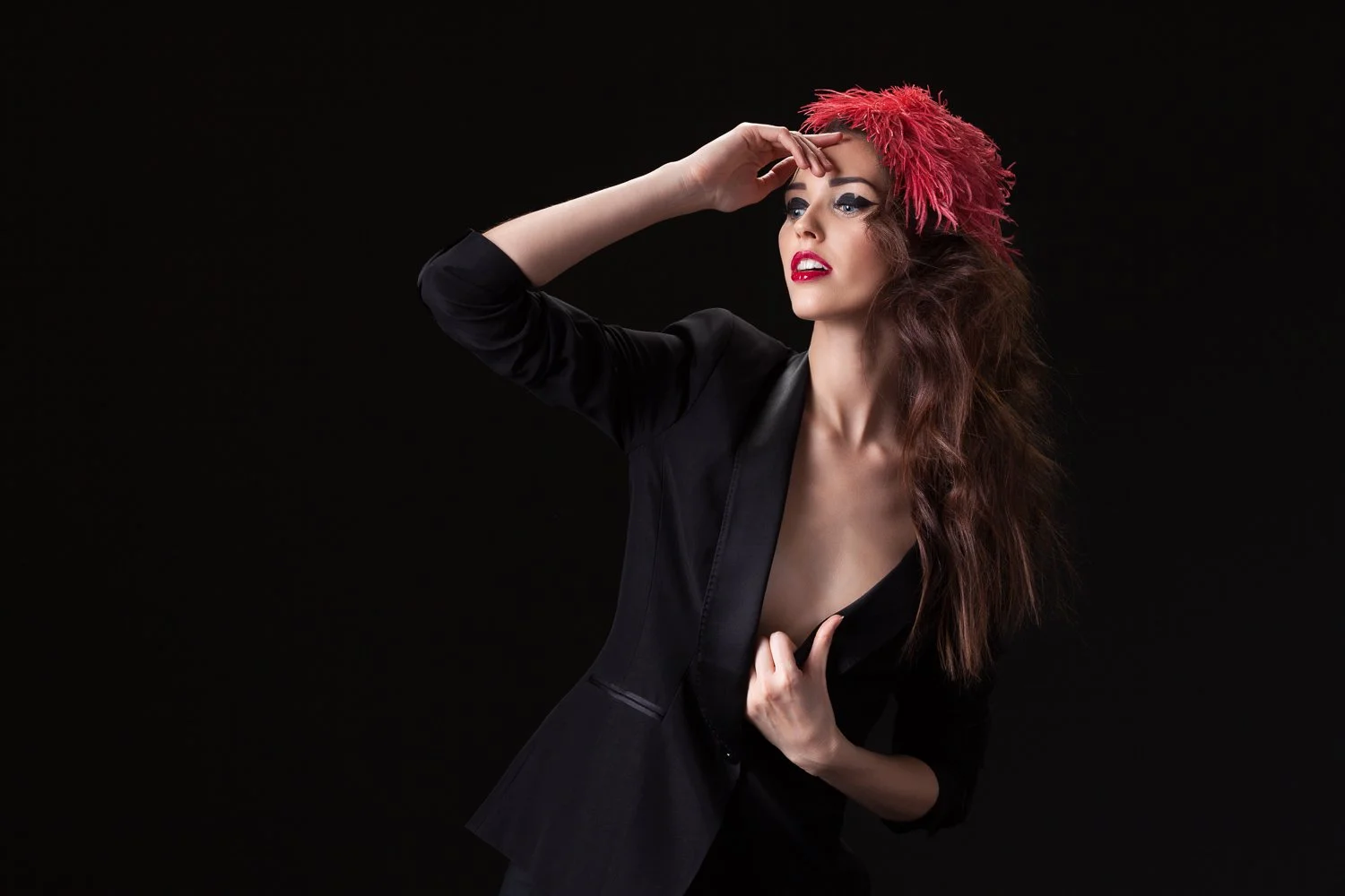 Model in a red feathered headpiece and black jacket, hand raised to her forehead, styled and art directed by Laurence Trolet, branding photography