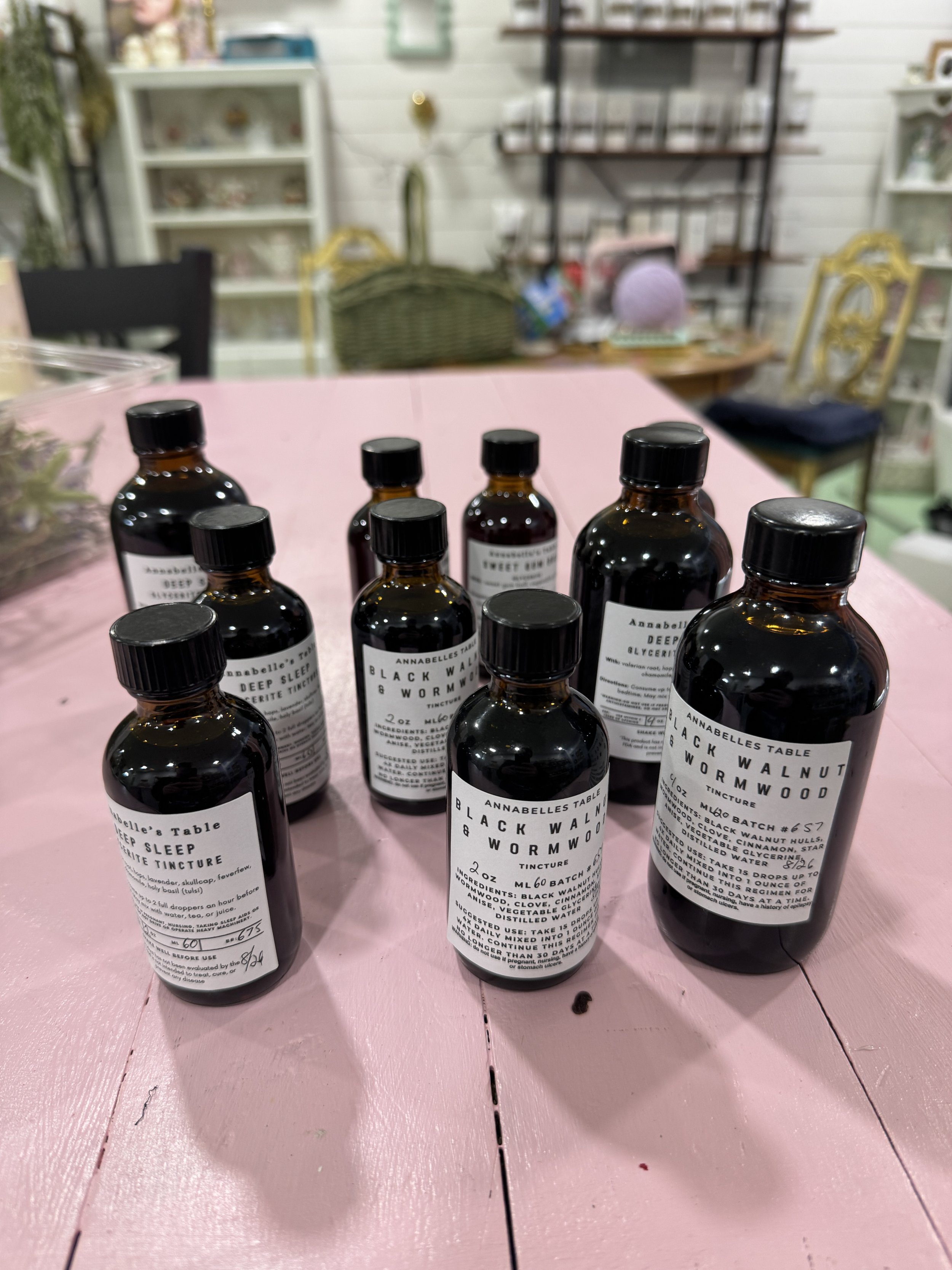 several bottles of various herbal tinctures lined up on pink table