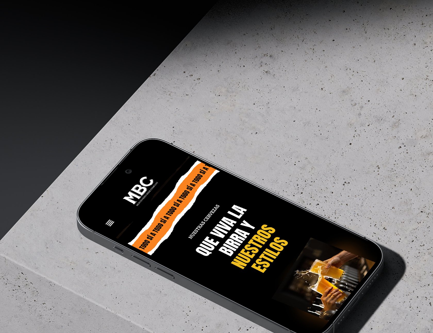 Teléfono móvil en una mesa con la pantalla encendida, mostrando una página web del sitio MBC sobre estilos y gustos, con una imagen de personas brindando con cervezas.