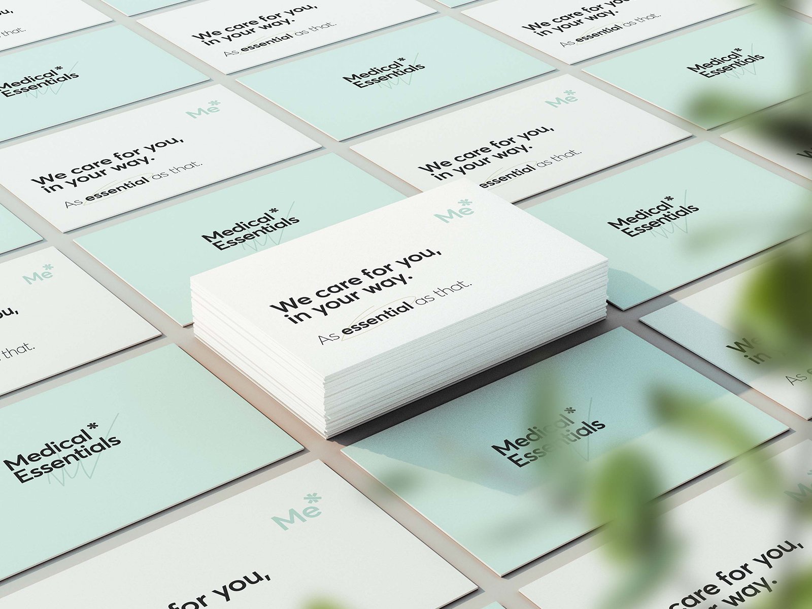 Conjunto de tarjetas de presentación blancas y celestinas con el texto "We care for you in your way! As essential as that" y "Medical Essentials" en diferentes posiciones, algunas apiladas formulando una pila en el centro.