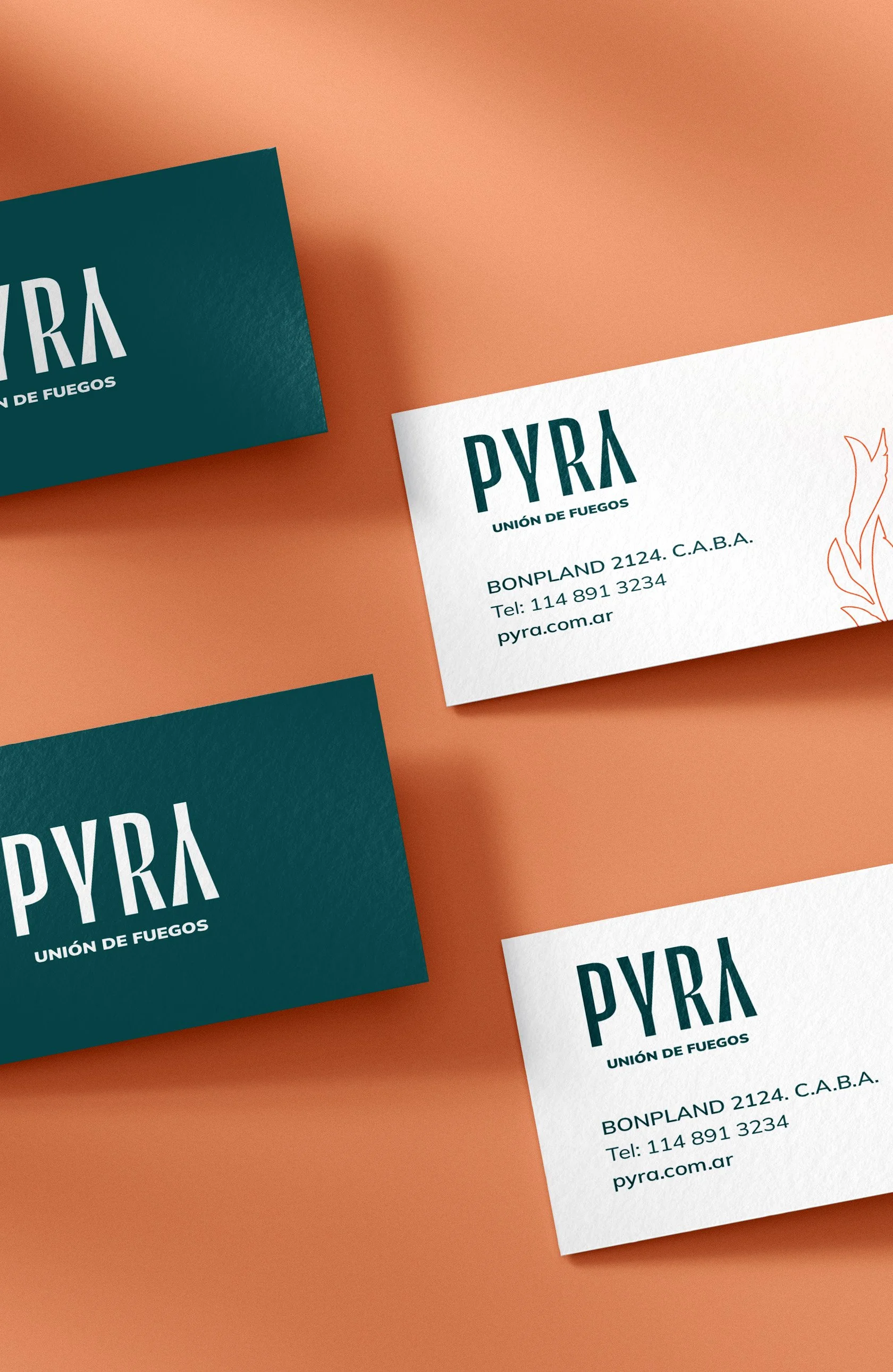 Tarjetas de presentación con el logo y datos de contacto de PYRA, unión de fuegos, sobre una superficie de color coral.