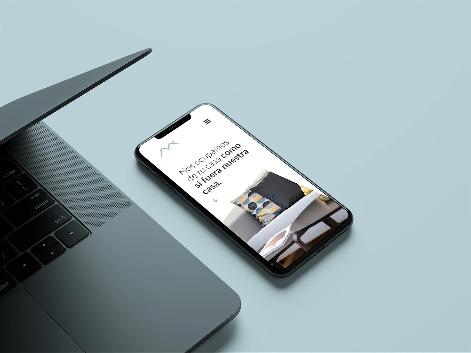 Teléfono móvil con una página web de decoración de interiores y un sofá con cojines coloridos
