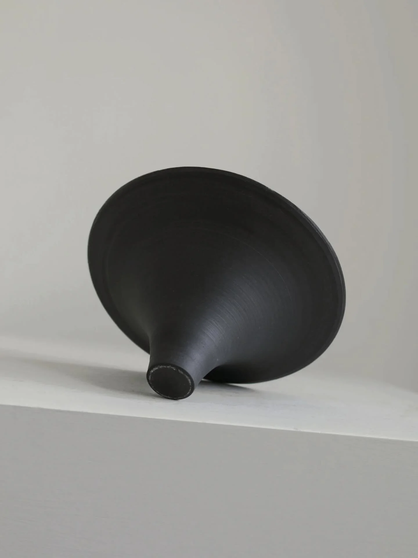 Studio pottery bowl thrown in matt black porcelain. Modernist form featuring a small base and conical flared rim. Unglazed finish.