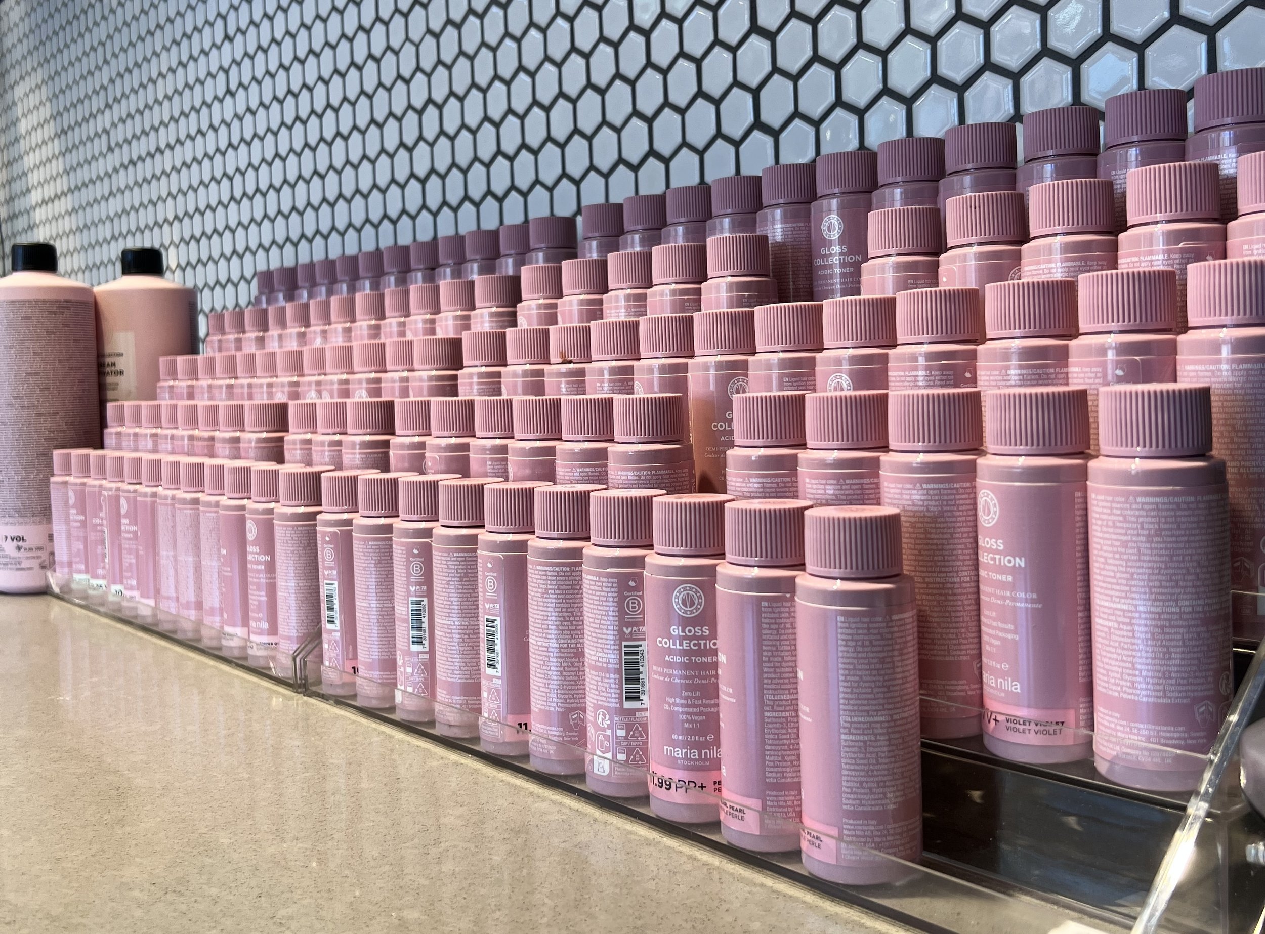 Maria Nila professional hair color products organized on the color bar at The Gilded Lily Chicago salon, including permanent color, glosses, and lightening products.