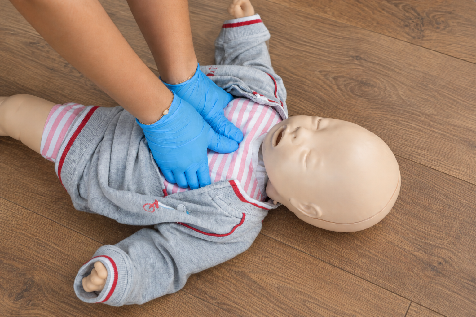 Person performing CPR on a baby mannequin during a training session.
