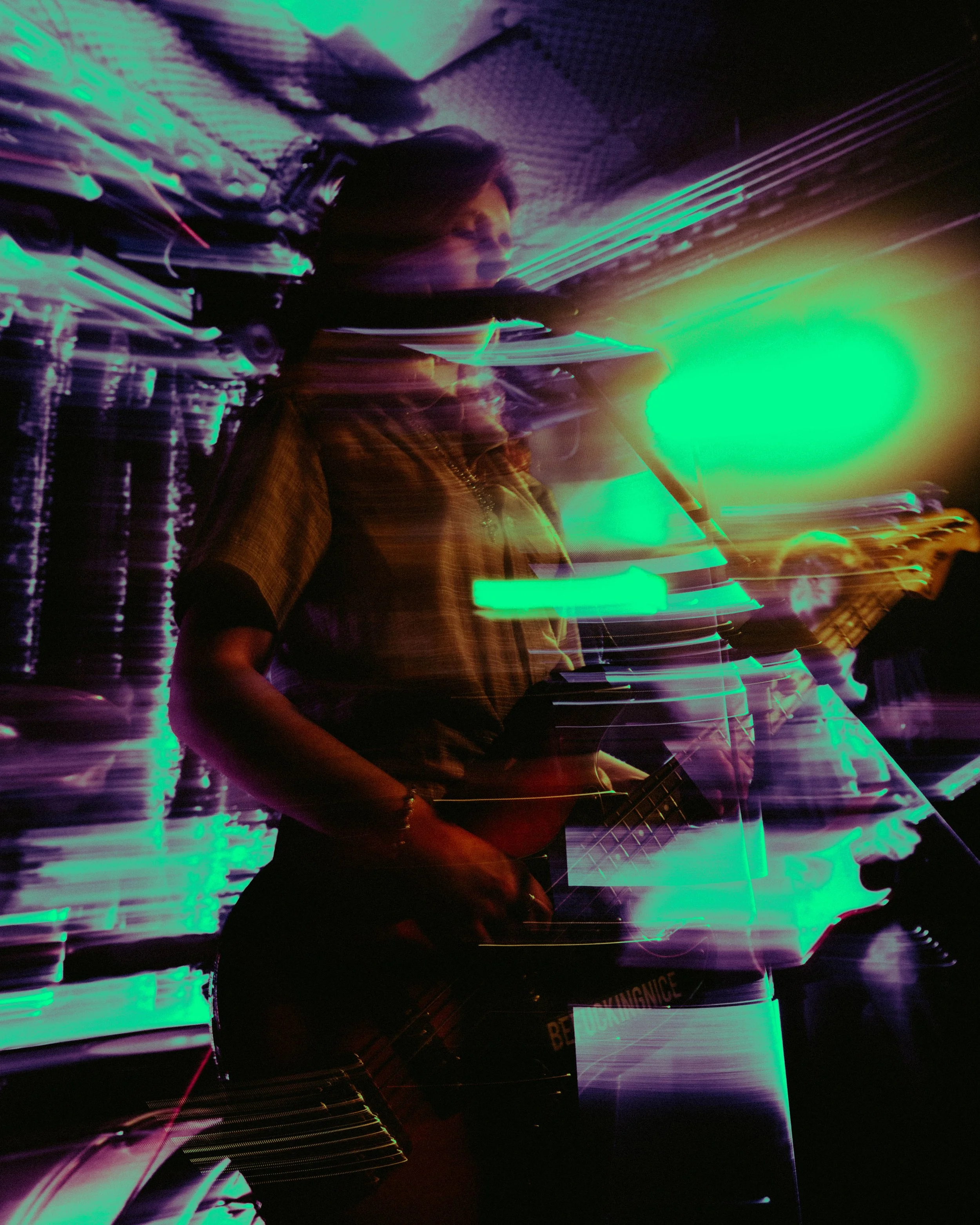 A person playing the guitar with colorful light trails in a dark room, creating a vibrant, abstract visual effect.