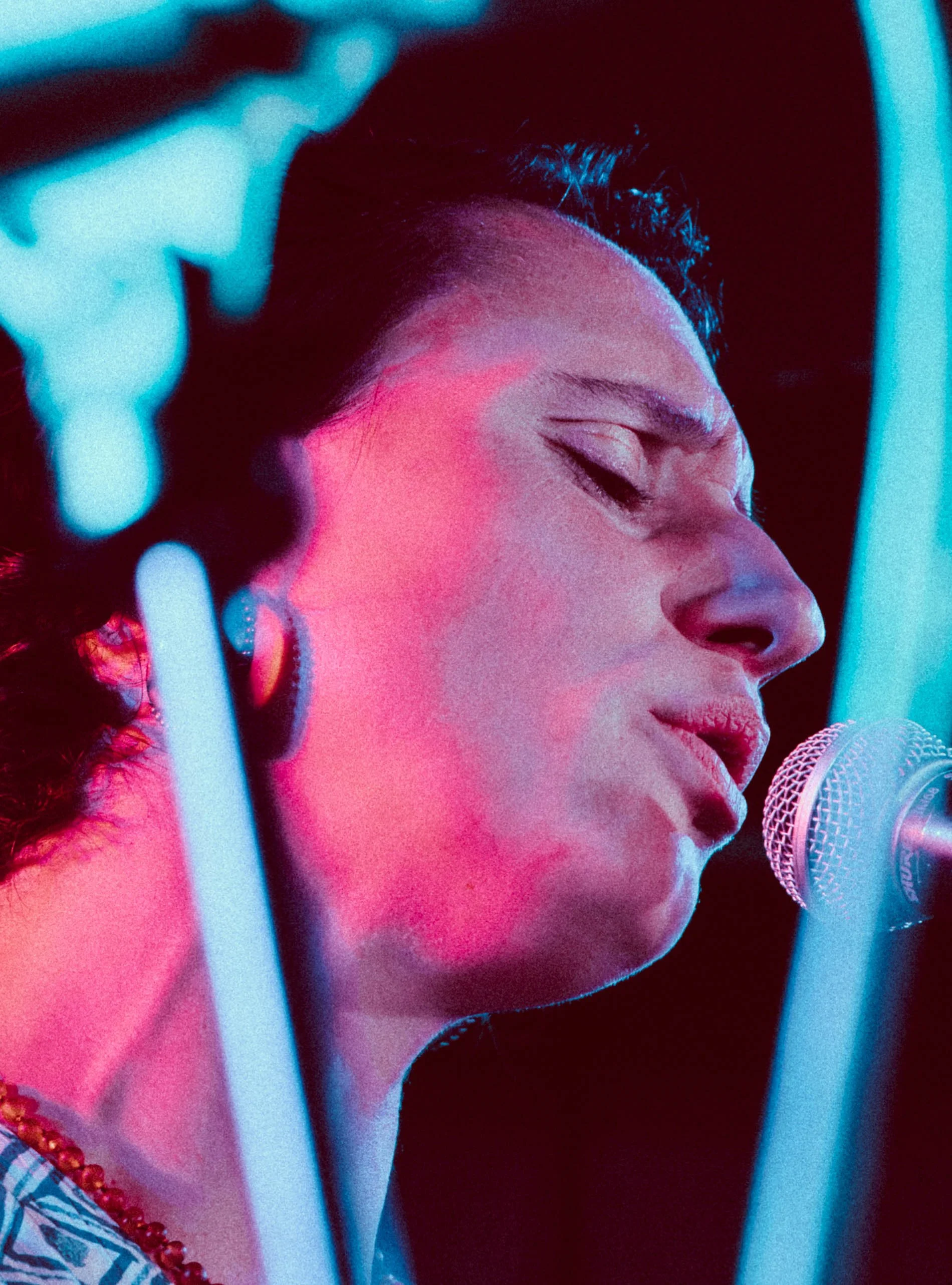Close-up of a woman singing into a microphone with colorful lighting.