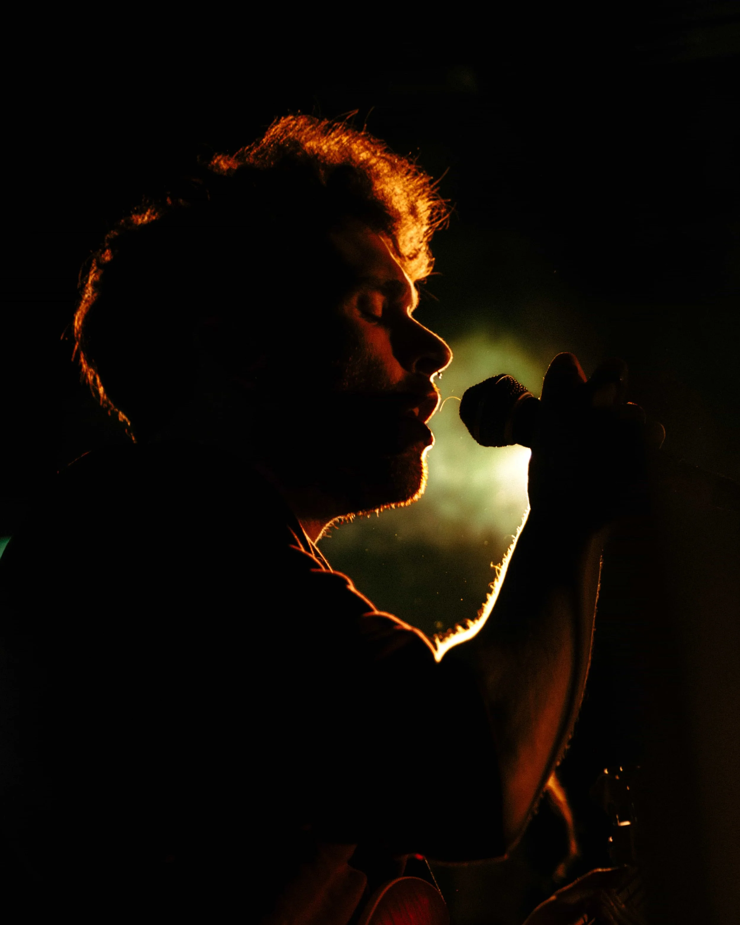 Silhouette of a person singing into a microphone with backlighting