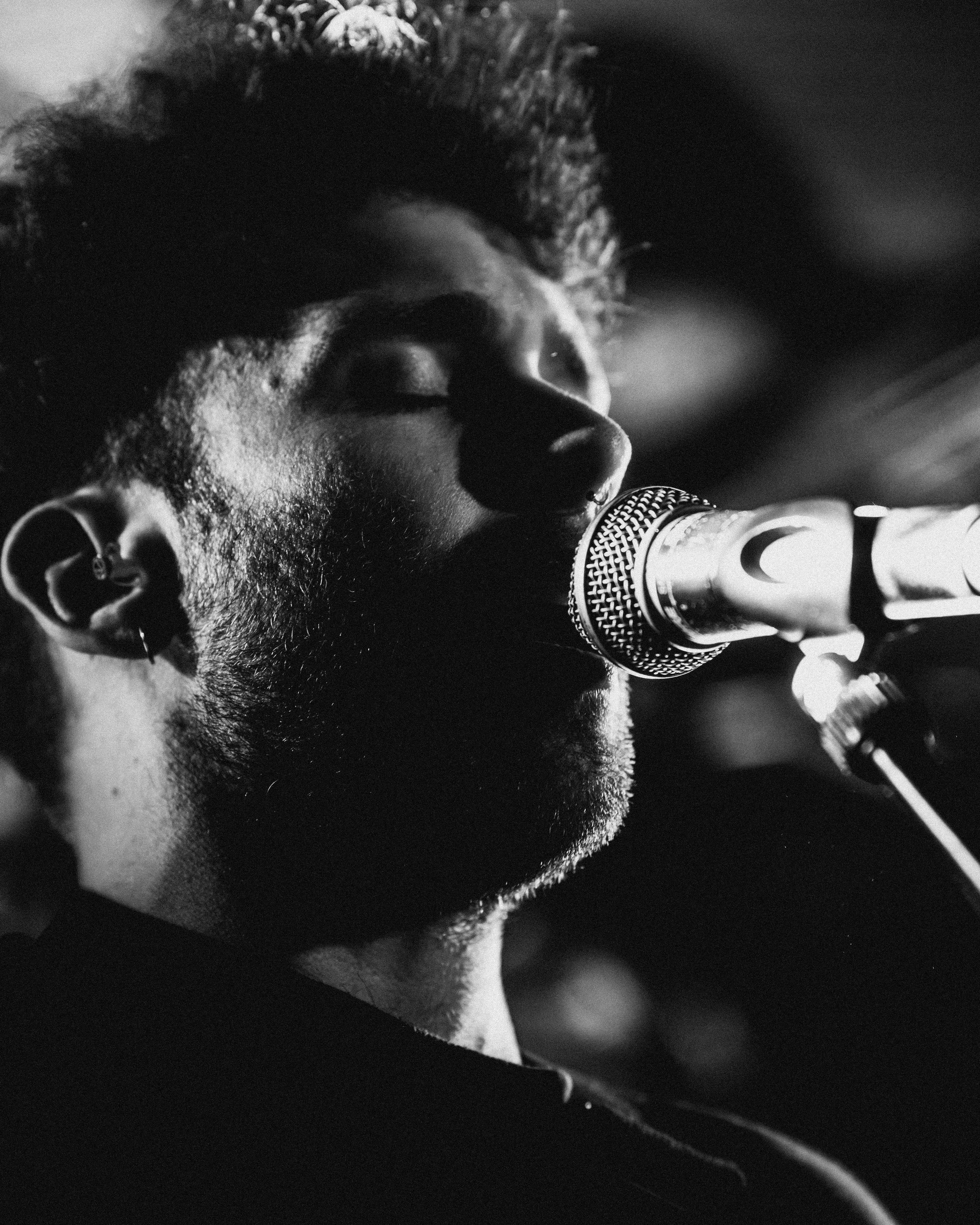 A person singing into a microphone with eyes closed, black and white photo.
