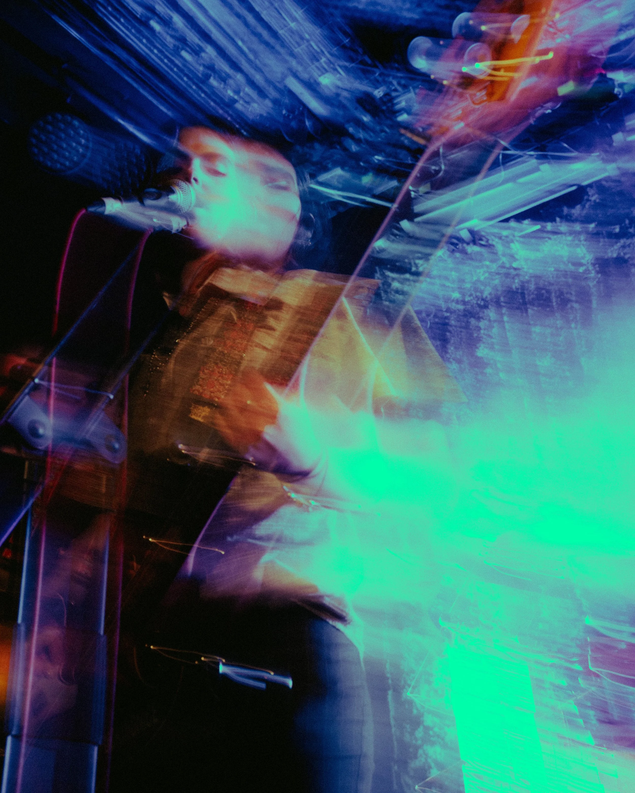 A musician singing into a microphone with colorful light trails and abstract effects surrounding them.