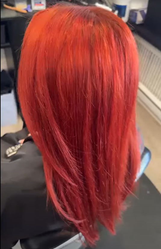 Side view of a person with shoulder-length, vibrant red hair.